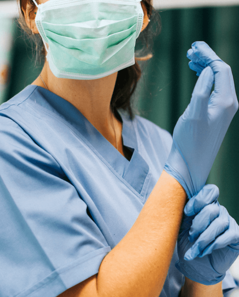 A healthcare provider is seen putting on gloves